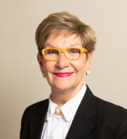 Smiling woman wearing yellow glasses and blazer