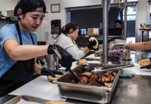 Kitchen staff slicing and serving roasted meat