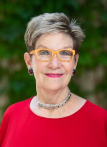 Smiling woman with short gray hair, yellow glasses