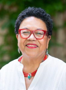 Smiling person wearing red glasses and necklace
