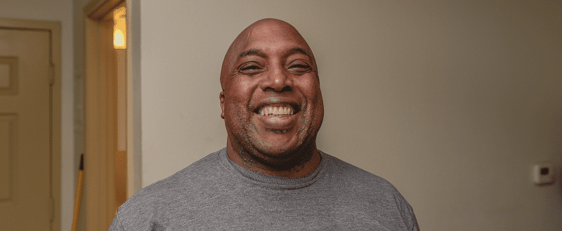 A picture of Greg smiling in his apartment