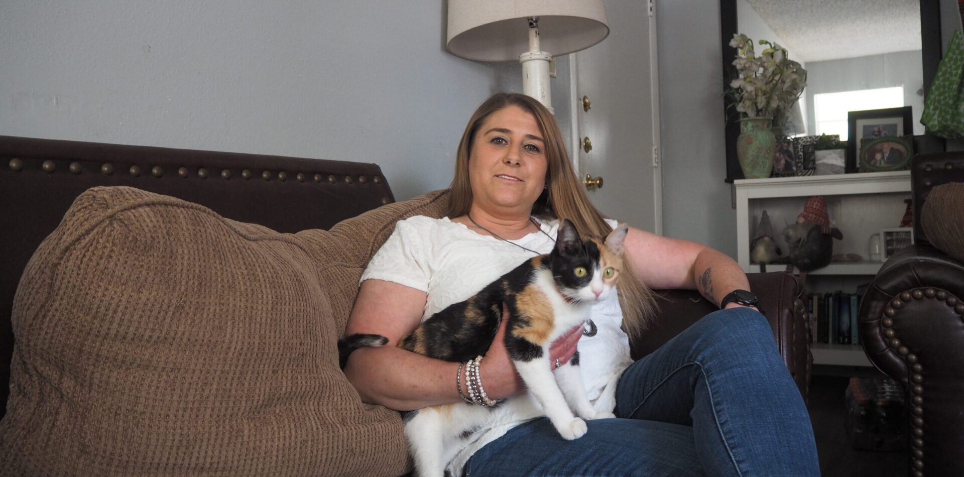 Woman sitting on couch holding calico cat