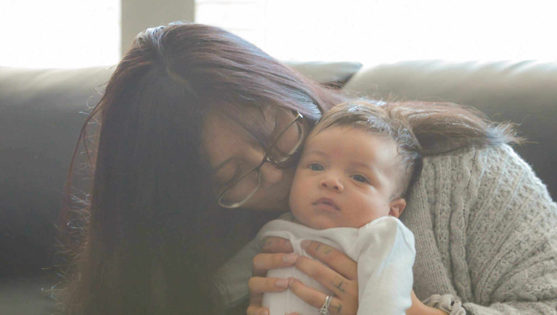 Woman kissing baby on couch