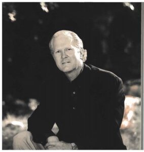 Older man seated outdoors wearing dark jacket
