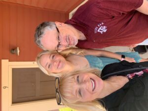 Three smiling adults on front porch