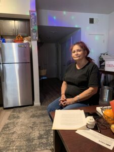 Woman in kitchen glancing at papers on table