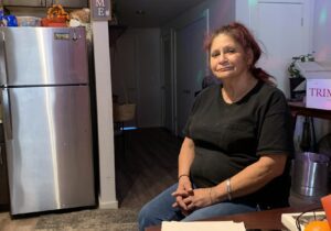Woman seated near refrigerator and papers