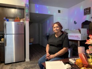 Seated woman in kitchen with paperwork nearby