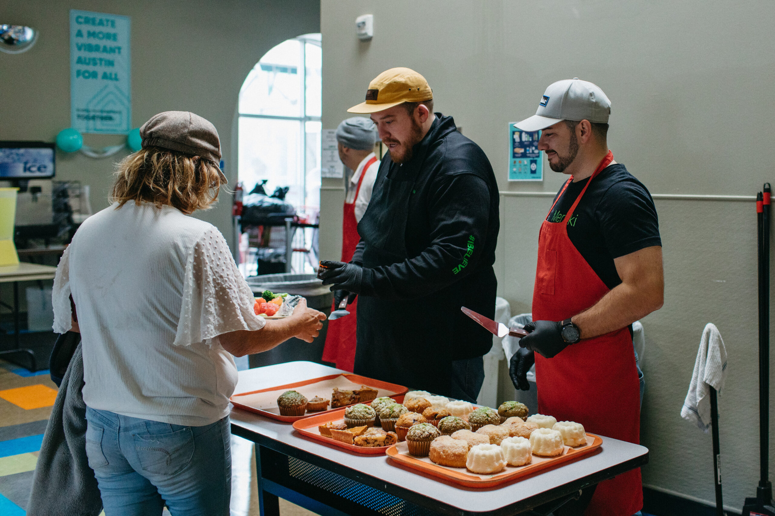 Volunteers serving muffins at community food table