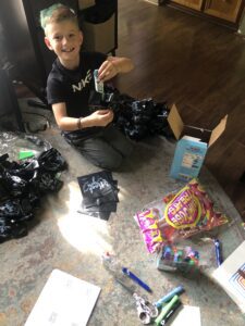 Smiling boy assembling party favor bags on floor