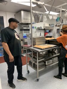 Two workers preparing trays in a commercial kitchen