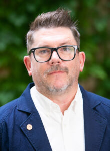Man with glasses and blazer outdoors