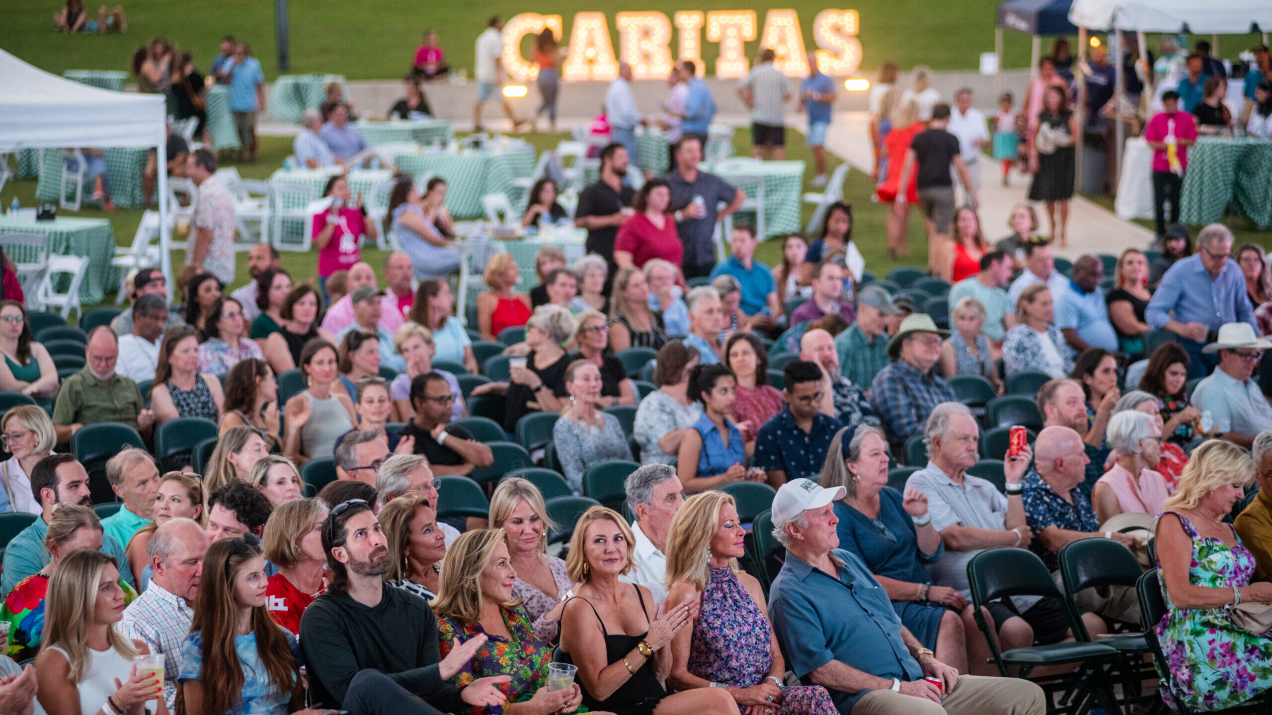 Large outdoor audience seated at evening concert
