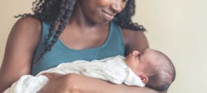 Woman cradling newborn baby, tender smile