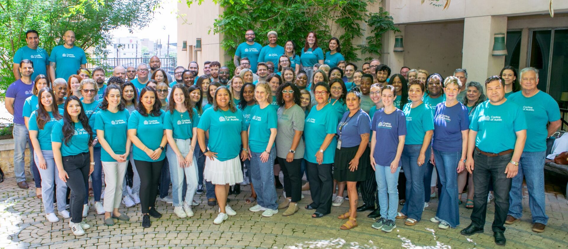 Group of people posing outdoors in teal shirts