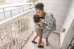 Smiling woman hugging child on balcony