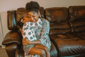 Mother and daughter embracing on leather couch