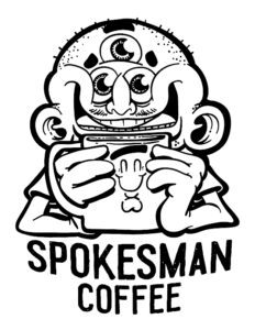 Three-eyed mascot holding Spokesman Coffee cup