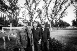 Three men standing by wooden fence outdoors