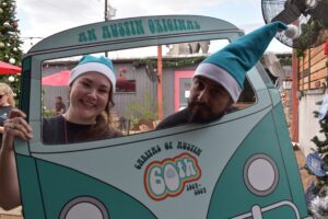 Two people wearing teal Santa hats behind van