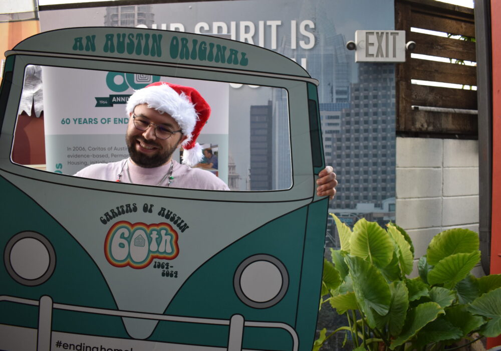 Smiling man wearing Santa hat behind van cutout