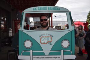 Smiling person behind Austin-themed van cutout