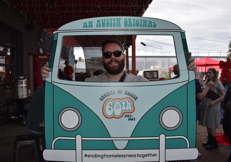 Smiling person behind Austin-themed van cutout