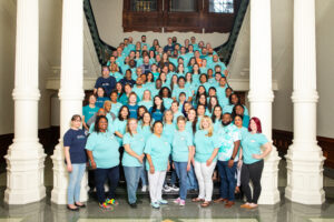 Large group wearing teal shirts on staircase