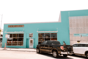 Turquoise storefront with parked black pickup truck