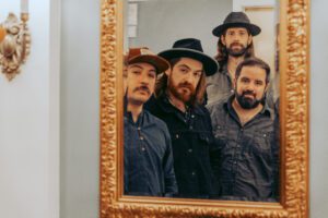 Four bearded men reflected in ornate mirror