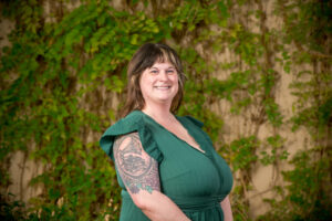 Smiling woman in green dress, tattooed arm